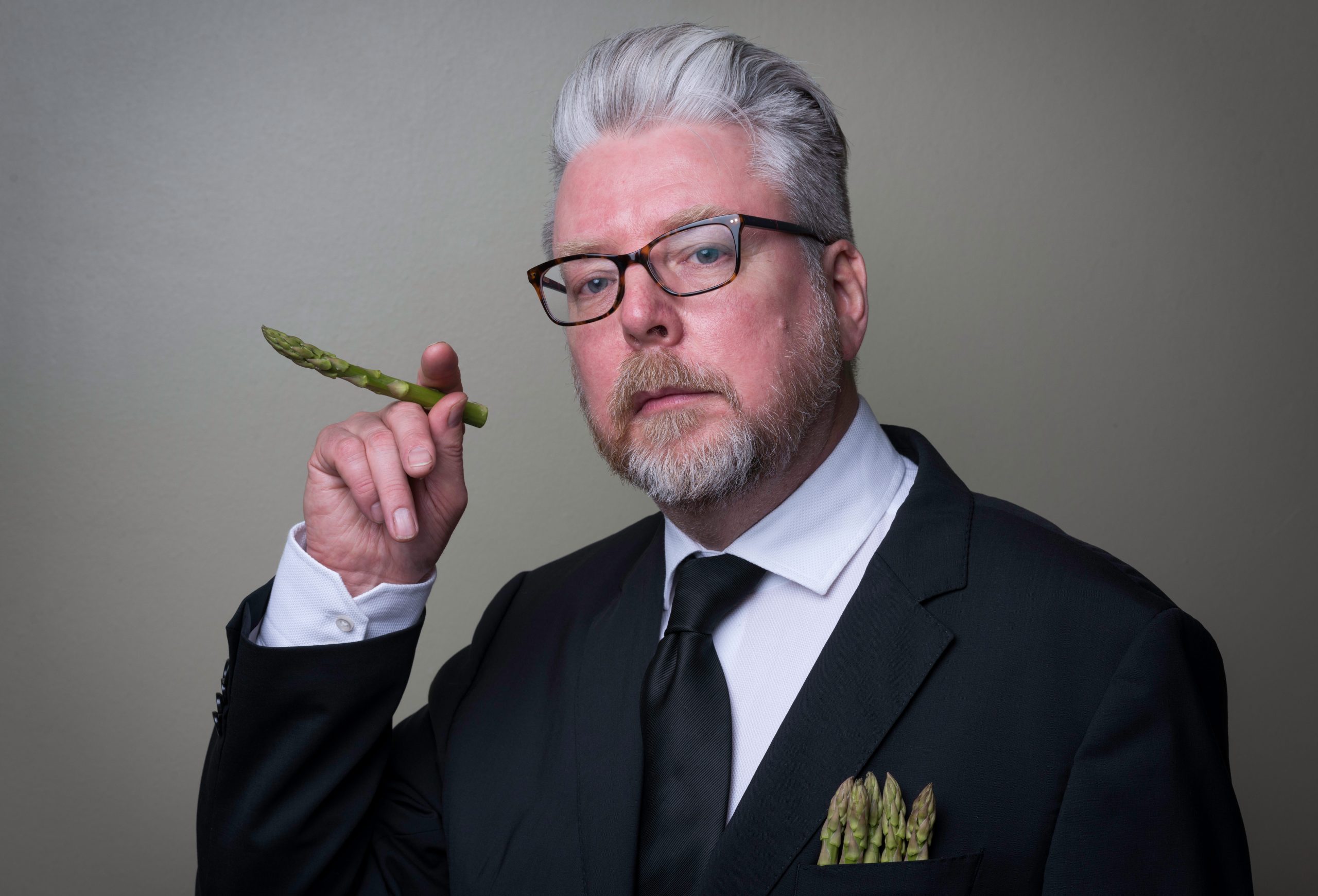 A PR related portrait of a Chef from the Assembly House, Norwich, holding asparagus like a cigar.